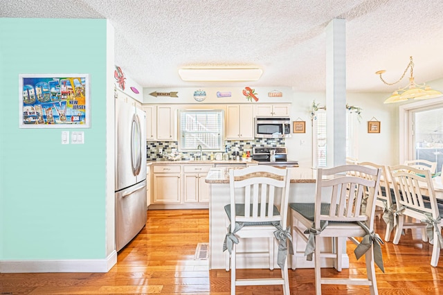 kitchen featuring plenty of natural light, decorative backsplash, a textured ceiling, and appliances with stainless steel finishes