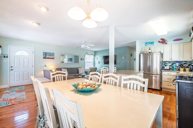 dining space with a ceiling fan, a textured ceiling, and hardwood / wood-style flooring