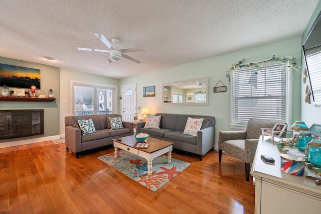 living area with plenty of natural light, a ceiling fan, a textured ceiling, and wood finished floors