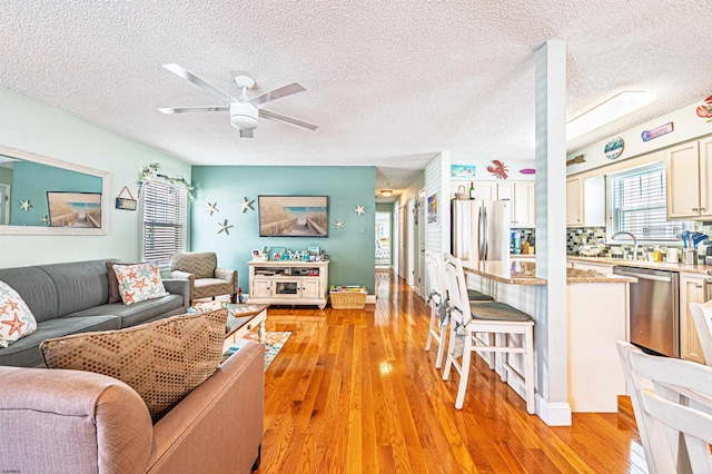 living area with light wood-style flooring, a textured ceiling, and ceiling fan