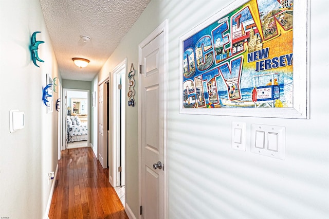 hallway with hardwood / wood-style floors and a textured ceiling