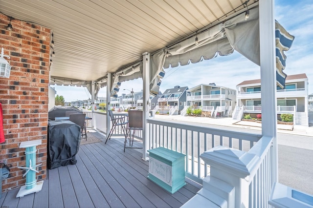 wooden terrace with covered porch, a residential view, and a grill