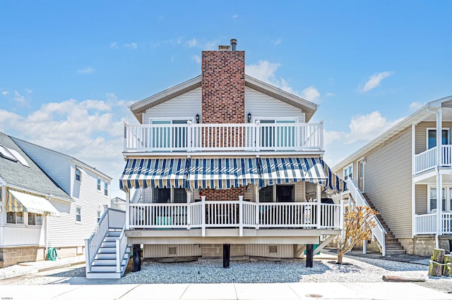 rear view of house featuring stairway, crawl space, a chimney, and a deck