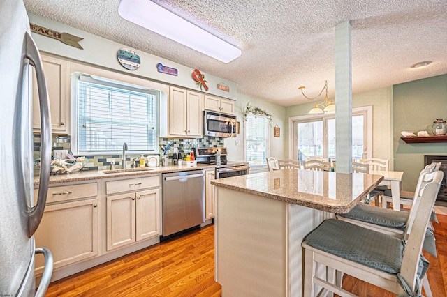 kitchen featuring plenty of natural light, a sink, a breakfast bar, and stainless steel appliances