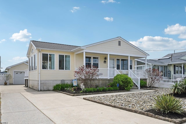 view of front facade featuring a detached garage, an outbuilding, a porch, and driveway
