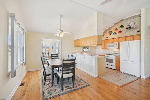 kitchen featuring white appliances, a ceiling fan, light wood finished floors, and a peninsula