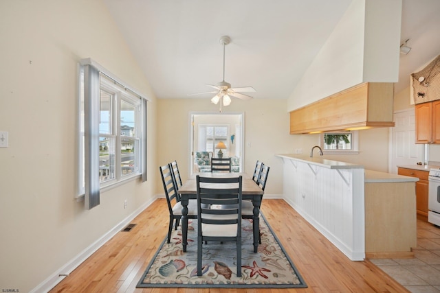 dining area featuring a ceiling fan, visible vents, baseboards, lofted ceiling, and light wood-style floors