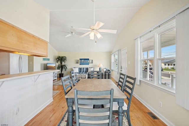 dining room featuring visible vents, light wood finished floors, ceiling fan, and vaulted ceiling