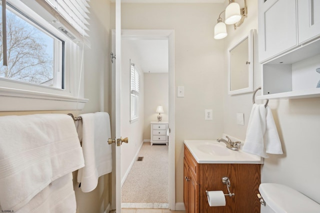 half bathroom featuring vanity, baseboards, visible vents, and toilet