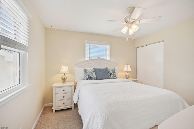 bedroom with a ceiling fan, baseboards, light carpet, and a closet