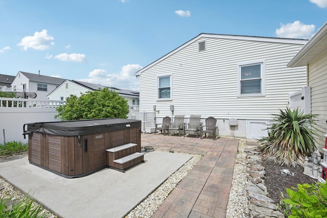 view of patio with a hot tub and fence