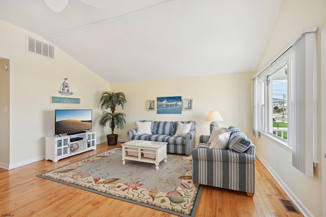 living area featuring baseboards, visible vents, wood finished floors, and vaulted ceiling