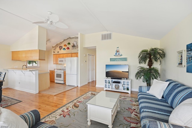 living area featuring visible vents, lofted ceiling, baseboards, ceiling fan, and light wood-type flooring