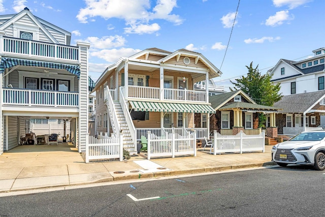 view of front facade featuring fence, covered porch, and concrete driveway