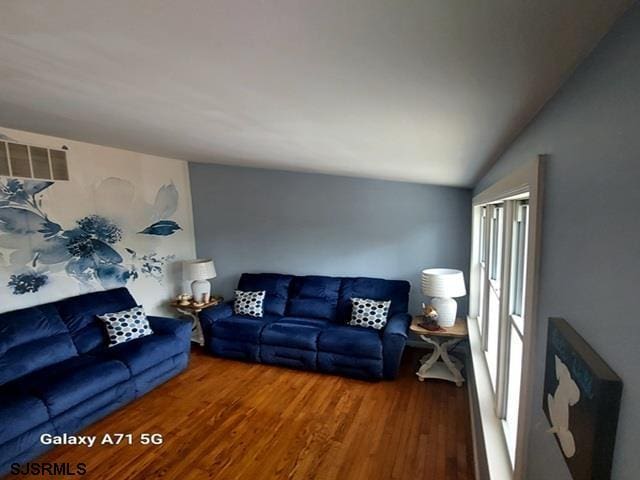 living area with visible vents, lofted ceiling, and wood finished floors