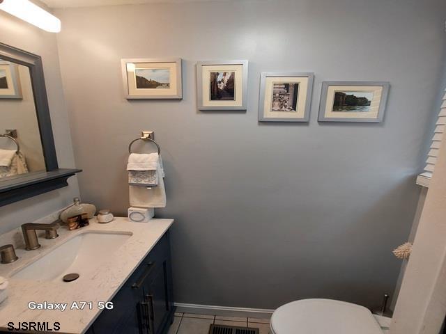 bathroom with toilet, visible vents, tile patterned flooring, and vanity