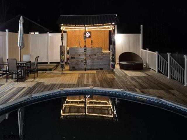 pool at twilight featuring a fenced in pool, a wooden deck, and fence
