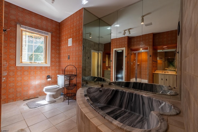 bathroom with vanity, a shower, toilet, tile patterned floors, and tiled bath