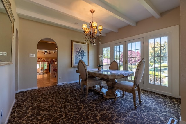 carpeted dining area with arched walkways, baseboards, beamed ceiling, and a notable chandelier