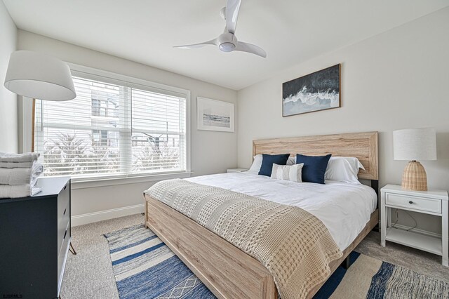 bedroom featuring light colored carpet, a ceiling fan, and baseboards