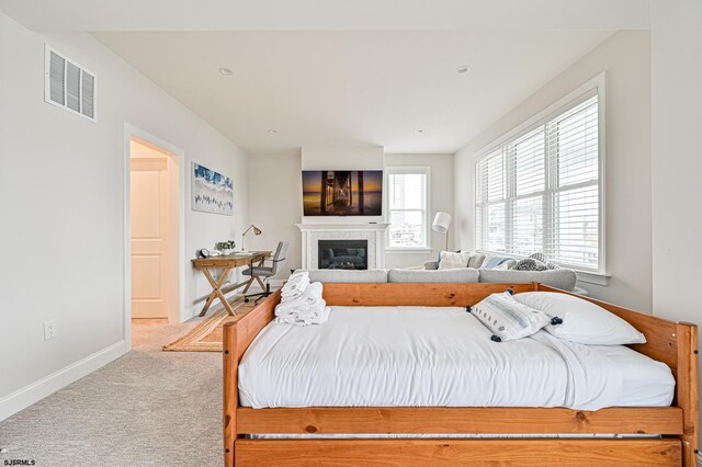 bedroom with carpet flooring, baseboards, visible vents, and a glass covered fireplace