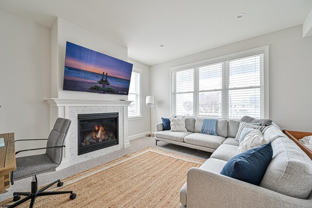 carpeted living room featuring baseboards and a premium fireplace