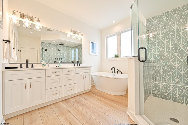 full bath with a sink, a stall shower, and wood finished floors