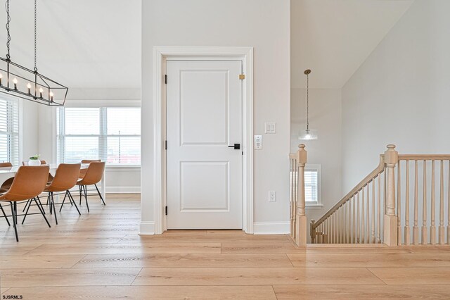 foyer with baseboards, an inviting chandelier, a healthy amount of sunlight, and hardwood / wood-style floors