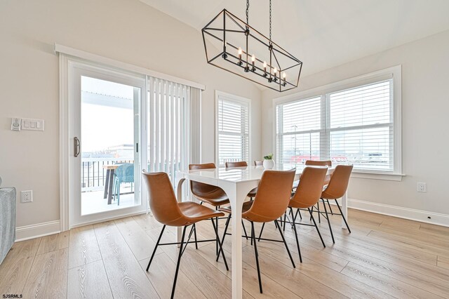 dining space featuring baseboards, a chandelier, and light wood-style flooring