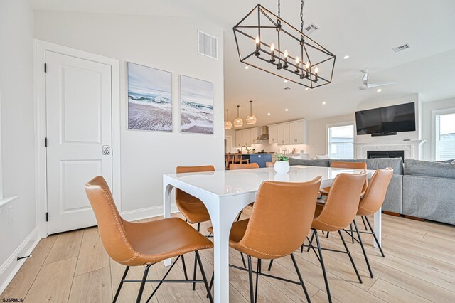 dining space featuring lofted ceiling, light wood finished floors, a chandelier, and visible vents