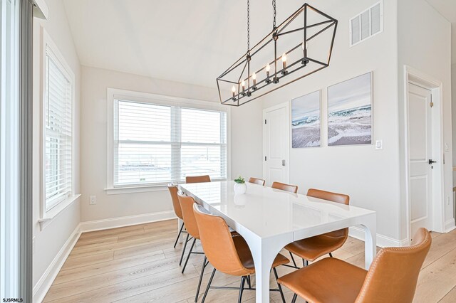 dining area with visible vents, light wood finished floors, baseboards, and an inviting chandelier