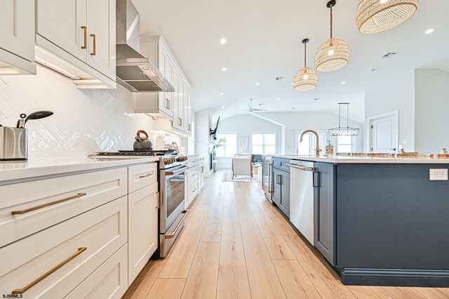 kitchen featuring recessed lighting, decorative backsplash, appliances with stainless steel finishes, and wall chimney range hood