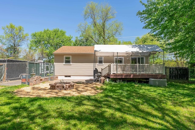 rear view of house with a lawn, fence, an outdoor fire pit, and a deck