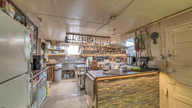 kitchen with freestanding refrigerator and concrete flooring