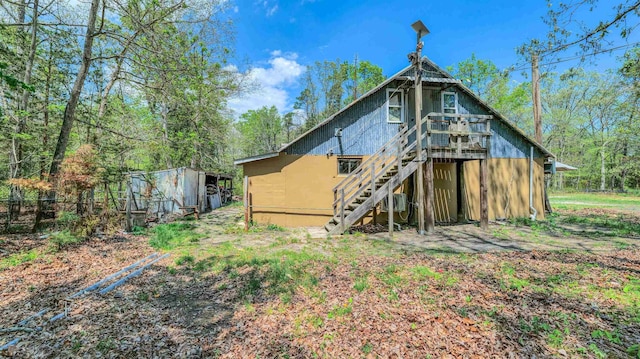 rear view of property featuring stairway, a wooden deck, an outdoor structure, and a storage unit