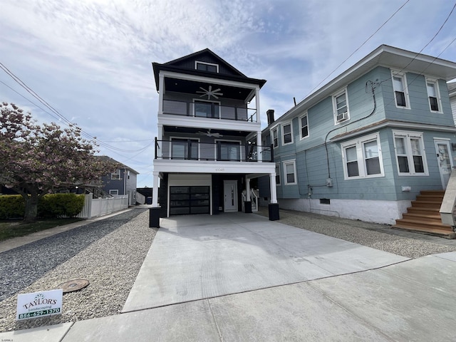 view of front facade with a ceiling fan, a carport, a balcony, concrete driveway, and an attached garage