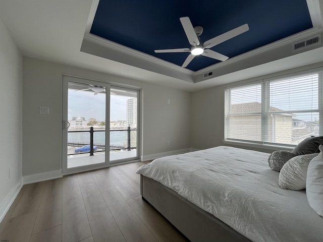 bedroom featuring visible vents, access to exterior, wood finished floors, a raised ceiling, and baseboards