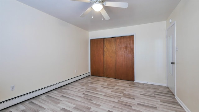 unfurnished bedroom with a closet, baseboards, light wood-style flooring, and a baseboard heating unit