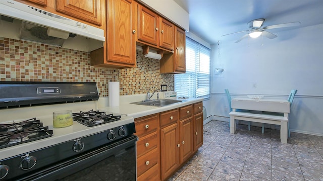 kitchen featuring ceiling fan, a sink, light countertops, range with gas stovetop, and under cabinet range hood