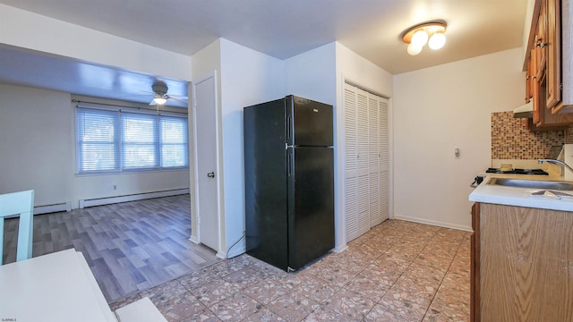kitchen with freestanding refrigerator, a sink, a baseboard radiator, and light countertops