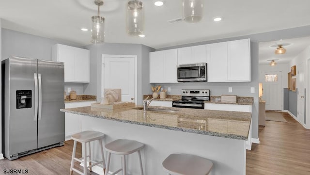 122 Hilton Ct, Egg Harbor Township, NJ 08234 - kitchen featuring appliances with stainless steel finishes, a sink, light wood finished floors, white cabinetry, and a kitchen bar