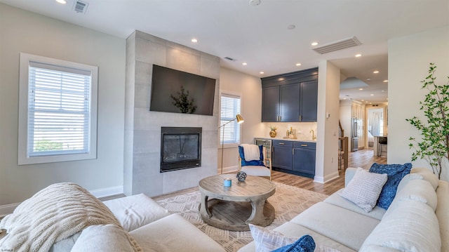 living room with baseboards, visible vents, light wood-style flooring, and a fireplace