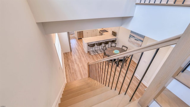 staircase featuring baseboards, a dry bar, and wood finished floors