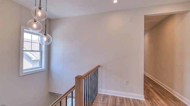 hallway with baseboards, recessed lighting, wood finished floors, and an upstairs landing