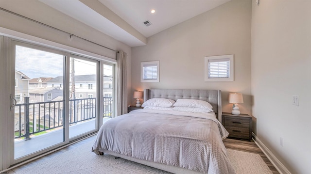 bedroom featuring baseboards, access to outside, multiple windows, and wood finished floors