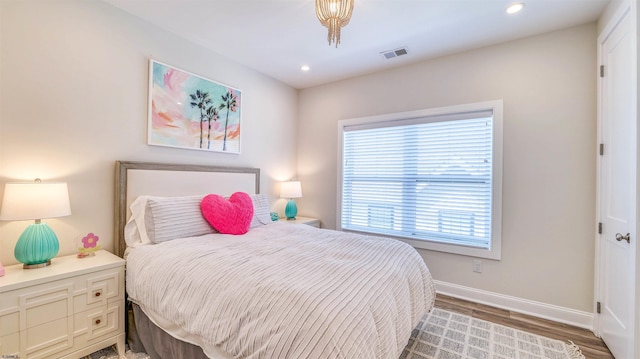 bedroom with baseboards, recessed lighting, wood finished floors, and visible vents