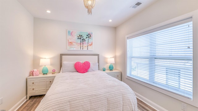 bedroom featuring light wood-style floors, baseboards, visible vents, and multiple windows