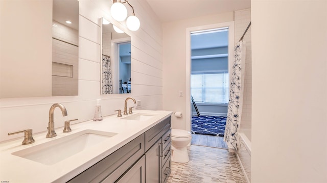 full bathroom featuring a sink, toilet, double vanity, and a shower with shower curtain