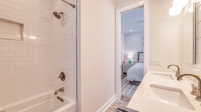 ensuite bathroom featuring baseboards, a sink, ensuite bath, and bathtub / shower combination