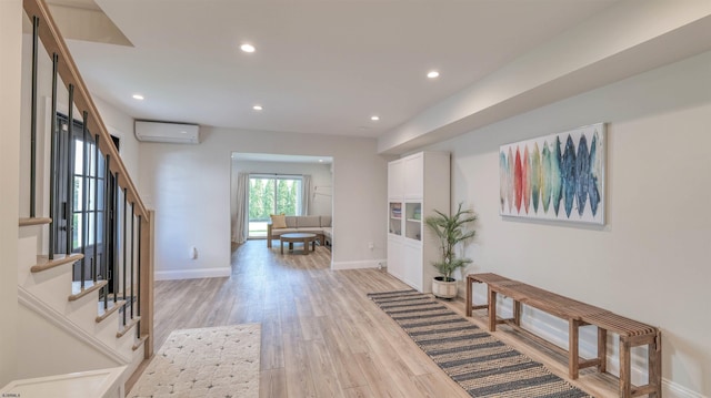 foyer entrance featuring a wall unit AC, light wood-type flooring, stairs, baseboards, and recessed lighting